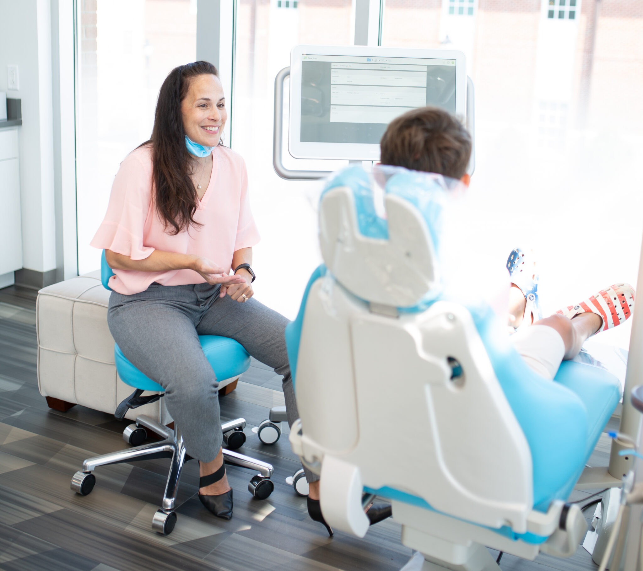 Dr. Rita McGrogan engaging with a patient in a modern orthodontic office, discussing Apex braces and personalized treatment options at Shine Orthodontics.